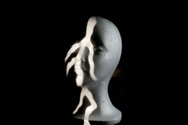 Yaratıcı ışıkların altında siyah bir arkaplana karşı büst heykelinin yakın çekimi