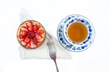Çilekli turta ve beyaz arka planda izole edilmiş bir fincan çay.