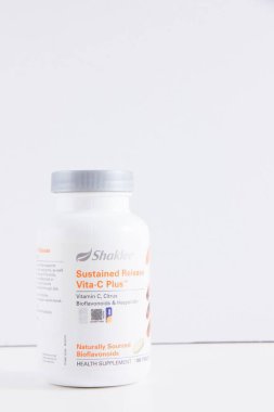 Beyaz bir duvara karşı, C vitamini beyaz bir plastik şişe 