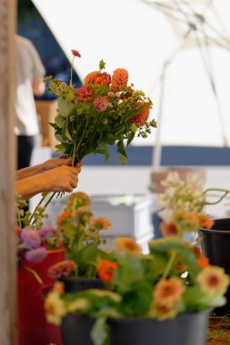 Bir satıcının dikey yakın çekimi yerel bir markette yetişen çiçeklerden buket yapıyor.