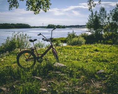 Göl kenarındaki çimlerin üzerine park etmiş bir bisiklet.