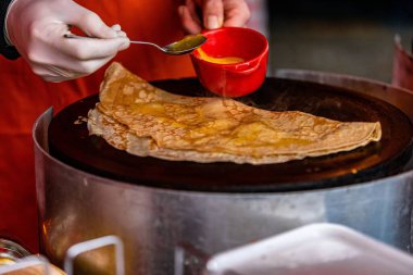 Ellerin yakın plan çekimleri, tavaya bal ekliyor.