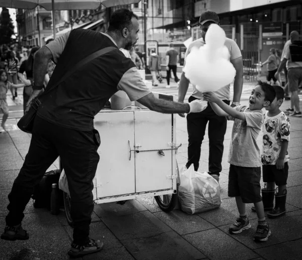 ストリートベンダーから綿菓子の棒を受信興奮した若い男の子のグレースケールショット — ストック写真