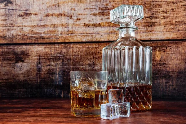 木製の背景にウイスキーとアイスキューブのガラスカップ — ストック写真