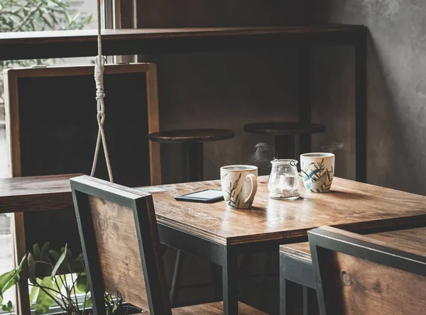 木のテーブルにはシンプルな2杯のコーヒーとタブレットが置かれたカフェの居心地の良いコーナー — ストック写真