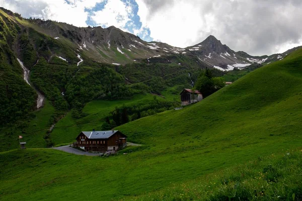 Vadinin Yeşil Yamaçlarındaki Kır Evi Bulutlu Gökyüzünün Altındaki Dağlar — Stok fotoğraf