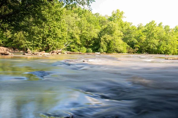背景に木が流れる川の美しい長時間露光ショット — ストック写真