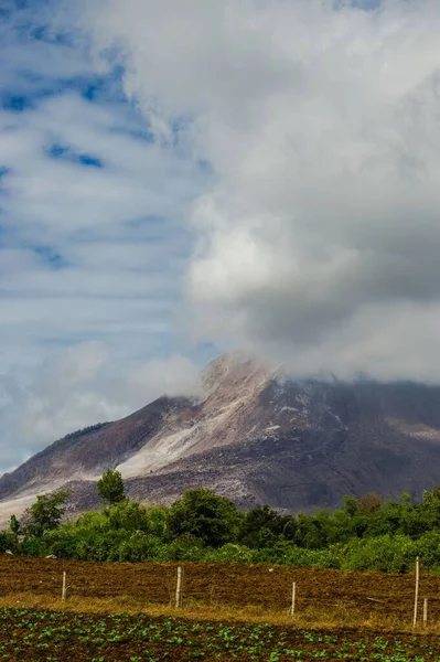 一张覆盖着白云的默拉皮火山峰的垂直照片 — 图库照片