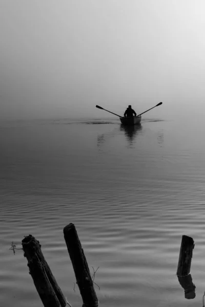 秋の霧の中の湖の上を舟で漕ぐ漁師の風景 — ストック写真
