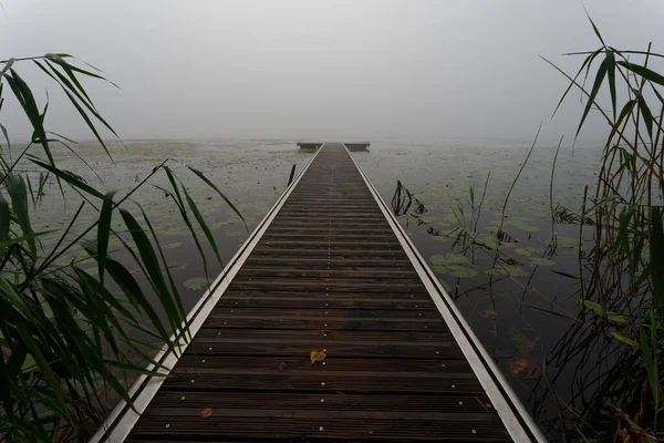 湖の秋の霧につながる神秘的な木製のジェティー — ストック写真