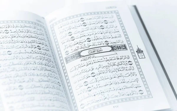 A closeup of an open Quran book with writings isolated on a white background