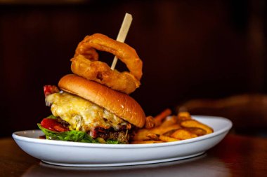 Ağız sulandıran New York burgeri, soğan halkaları ve patates kızartması.