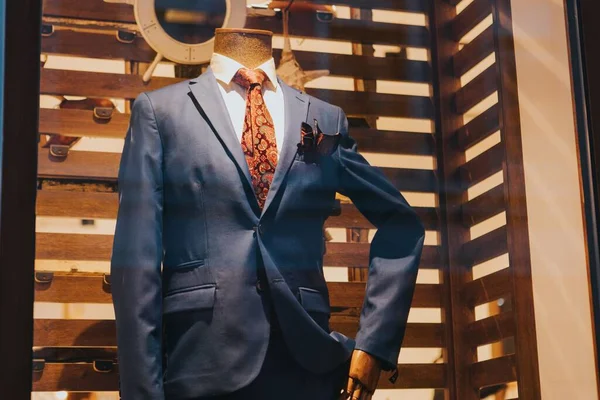 A closeup of a blue tuxedo with a red tie on a mannequin