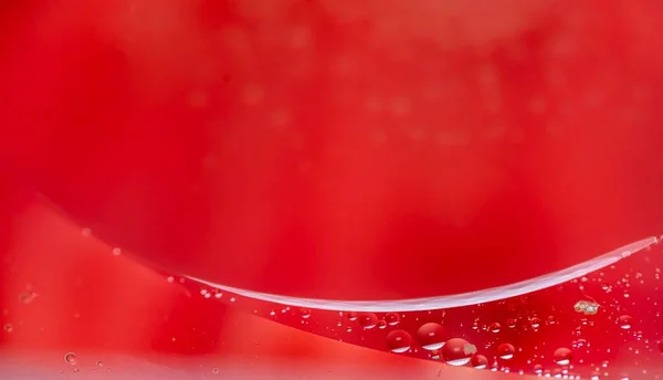 small drops of oil in water on redbackground. macro photo