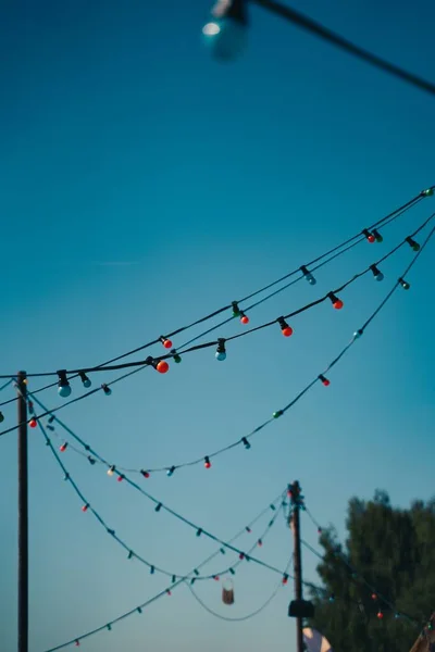青い空の背景に吊るされた光のガーランドの垂直ショット — ストック写真
