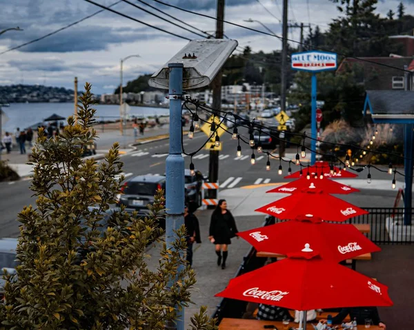 屋外のカフェの隣の通りを歩く人々の高い角度の赤いコカ コーラの傘 — ストック写真