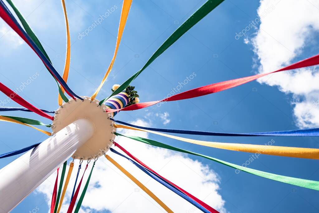 A low angle shot of the colorful bands of maypole on blue cloudy sky background