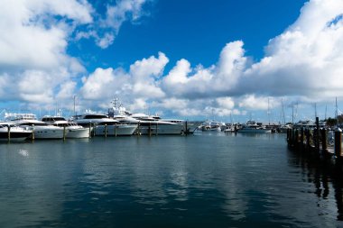 Üzerlerinde güzel bulutlu gökyüzü olan birkaç teknenin manzarası.