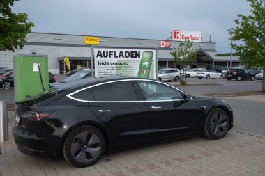 Lidl süpermarketinde çalışan siyah Tesla Model 3 çift motorlu şarj istasyonu.