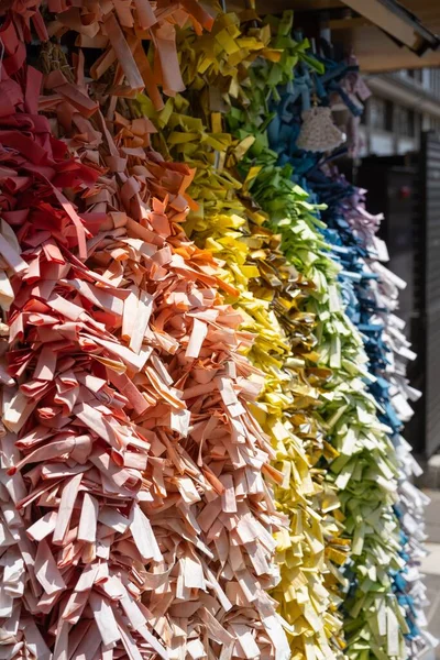 文字列に結び付けられた様々な色の占いの結果として紙が滑り落ちる日本の御子神 — ストック写真