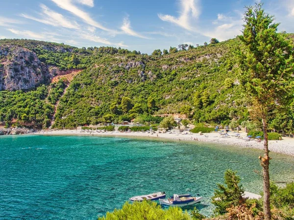 背景に山があるギリシャの素敵なビーチでボートとスコペロスの町のショット — ストック写真