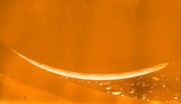 small drops of oil in water on orange background. macro photo