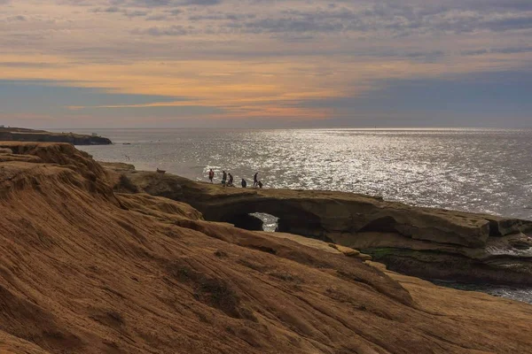 岩の多い海岸で夕日を楽しむ人々 — ストック写真