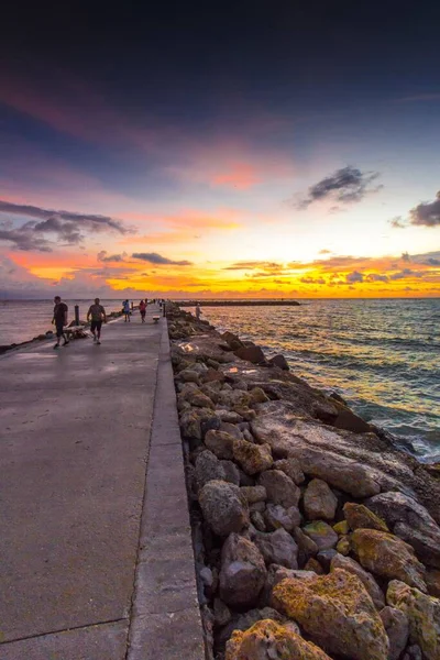 美しい夕日の海に向かって桟橋を歩く人々の垂直 — ストック写真