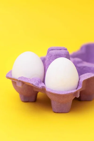 Sepasang Telur Dalam Kotak Telur Ungu Terisolasi Latar Belakang Kuning — Stok Foto