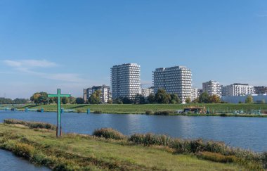 Arka planda binalar olan nehrin yanında bir haç.