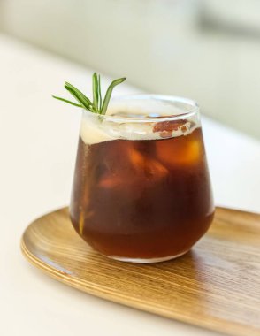 Tahta tepside bir bardak buzlu kahvenin dikey çekimi.