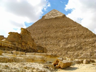 Bulutlu bir gökyüzünün altında Büyük Giza Piramidinin alçak açılı bir görüntüsü.