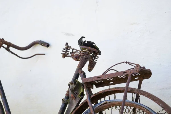 旧的锈迹斑斑的自行车靠在白墙上 特写镜头 — 图库照片