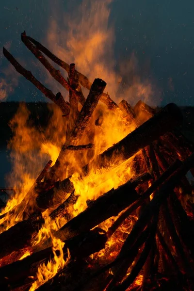 A vertical shot of flaming woods at a bonfire during nighttime