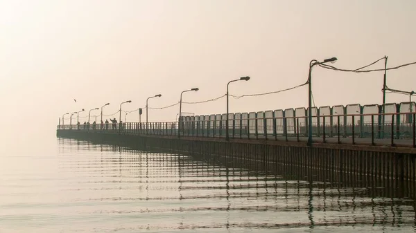 海の桟橋のワイヤーに接続されている街路灯は 霧の日に水に反射しています — ストック写真