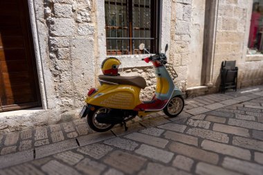 Hırvatistan 'ın Istria kentindeki bir binanın önünde güneşli bir günde sarı bir motosiklet.