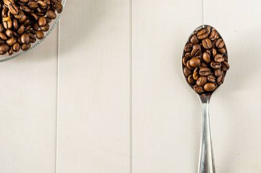 Kahve çekirdekleri metalik kaşık üzerinde, beyaz arka plan