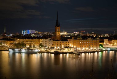 İsveç 'in Stockholm şehrinin kuş bakışı manzarası geceleyin bir nehire yansıyor.