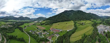 Dağ eteklerinde evleri ve ormanları olan bir tepenin havadan çekilmiş panoramik görüntüsü.
