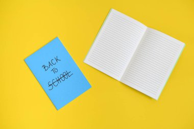 Okula geri dönen metin mavi bir not defterinin kapağında yazılıydı, parlak sarı arkaplanda açık bir defter.