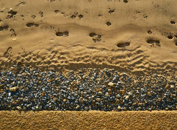 由人类 狗的脚步声和小石头构成的沙滩的顶部景观 — 图库照片