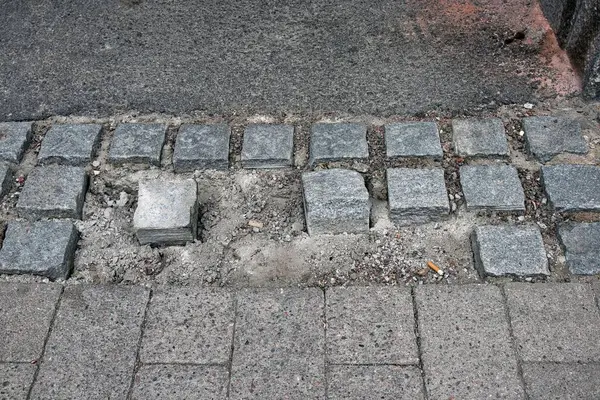 Sokak yolundaki gri gevşek kaldırım taşlarının yüksek açılı görüntüsü.