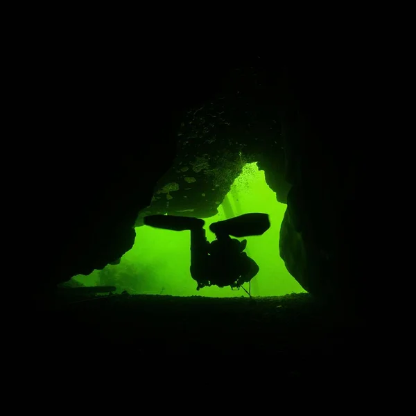 背景が緑の海の洞窟の中のダイバーのシルエット — ストック写真