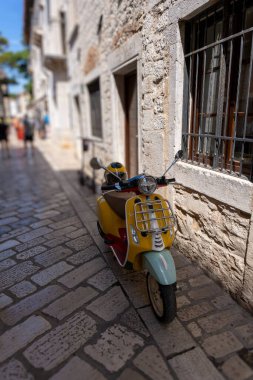 Güneşli bir günde Hırvatistan 'ın Istria kentindeki bir binanın önünden sarı bir motosiklet geçti.