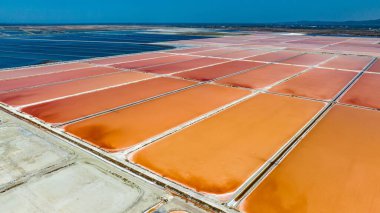 Arnavutluk 'un güneşli bölgelerinde kırmızı ve mavi tuz üretim havuzlarına bakan hava manzarası