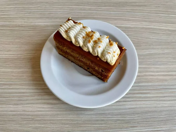 木製のテーブルの上に白いプレートにホイップクリームとトフィーケーキのクローズアップショット — ストック写真