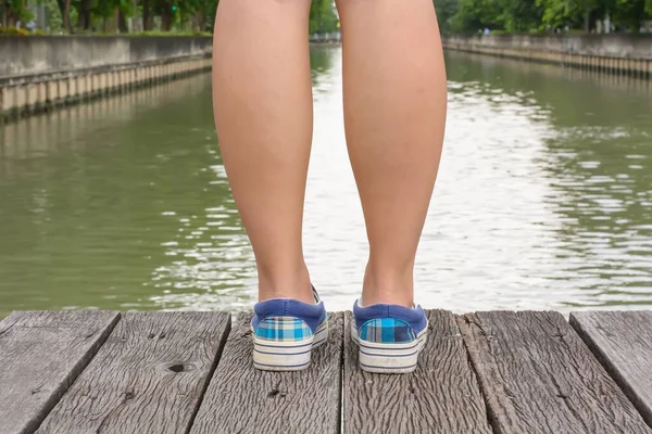 Zbliżenie Stóp Dziewczyny Noszącej Płócienne Trampki Stojące Drewnianym Moście — Zdjęcie stockowe