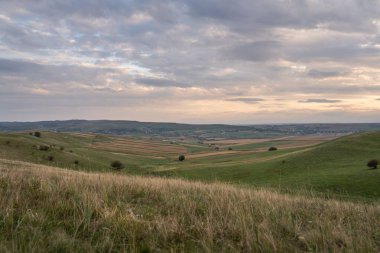 Arkaplanda uzanan engin yeşil vadilerin muhteşem manzarası bulutlu bir gökyüzünün altında