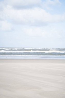 Arka planda bulutlu bir gökyüzü ve okyanus dalgalarının dikey görüntüsü..