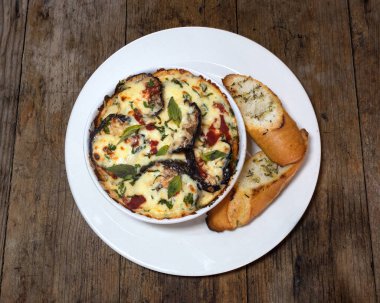 Patlıcan lazanyası, mozzarella peyniri, parmesan peyniri, fesleğen, maydanoz ve sarımsaklı ekmek.